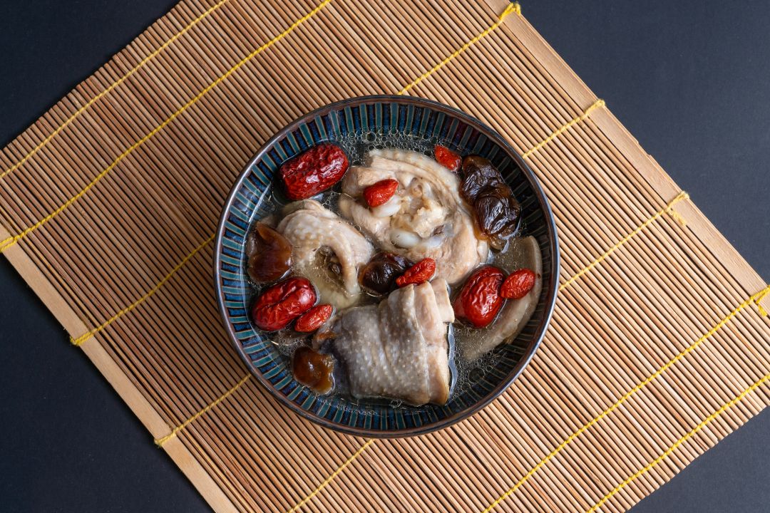 一碗香菇紅棗枸杞雞湯，盛裝在深藍色碗中，由上往下俯拍。