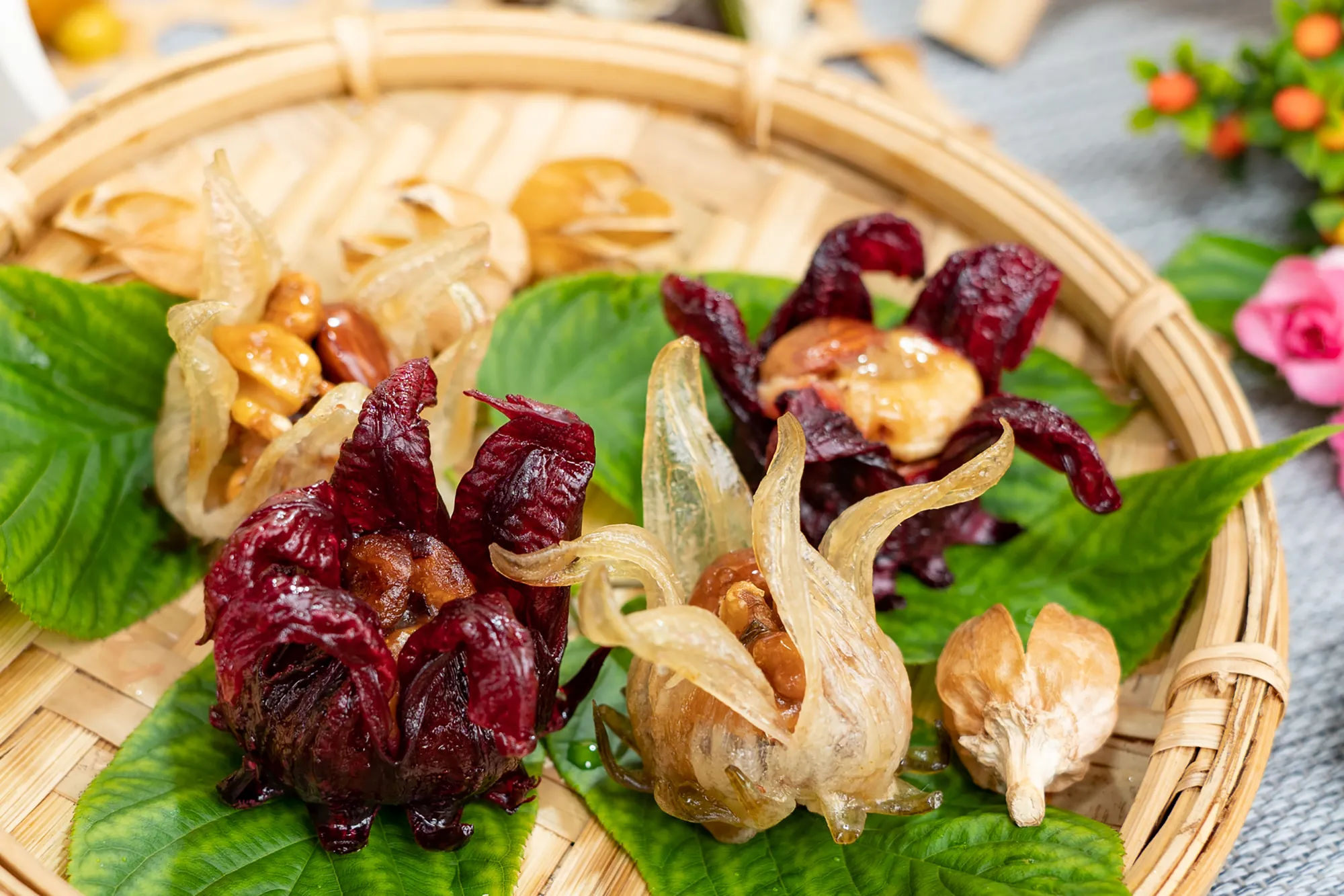 擺盤精緻的手工蜜漬洛神花甜點，包含深紅與金黃兩種色澤，中間鑲嵌脆口堅果，呈現酸甜滋味與豐富口感的創意養生茶點。