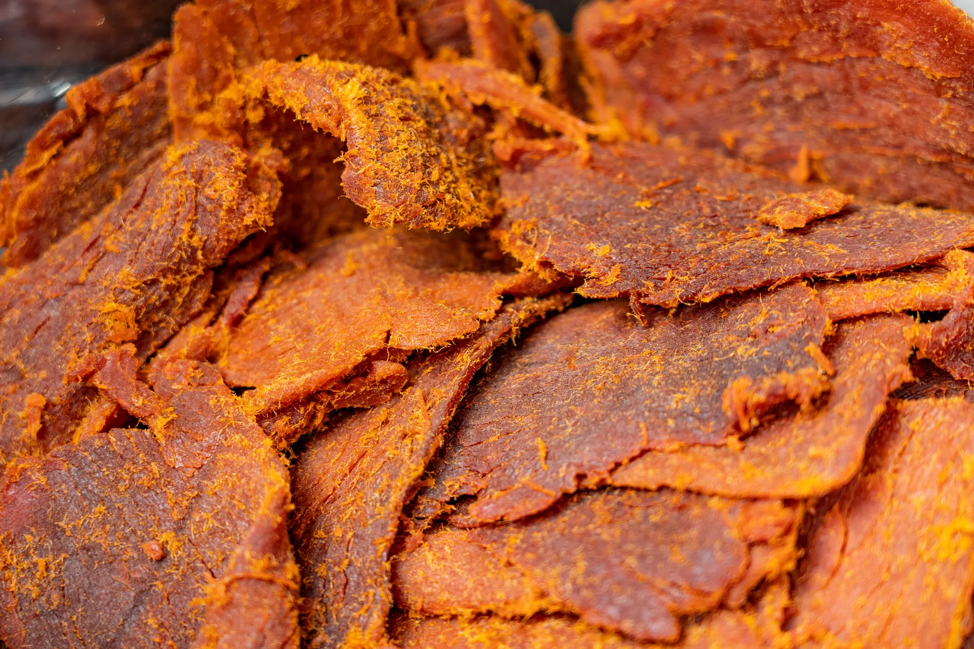 特寫鏡頭展示台灣傳統手撕豬肉乾的豐富纖維，呈現烘烤後的金黃色澤與紮實紋理，是具備嚼勁的經典茶點。