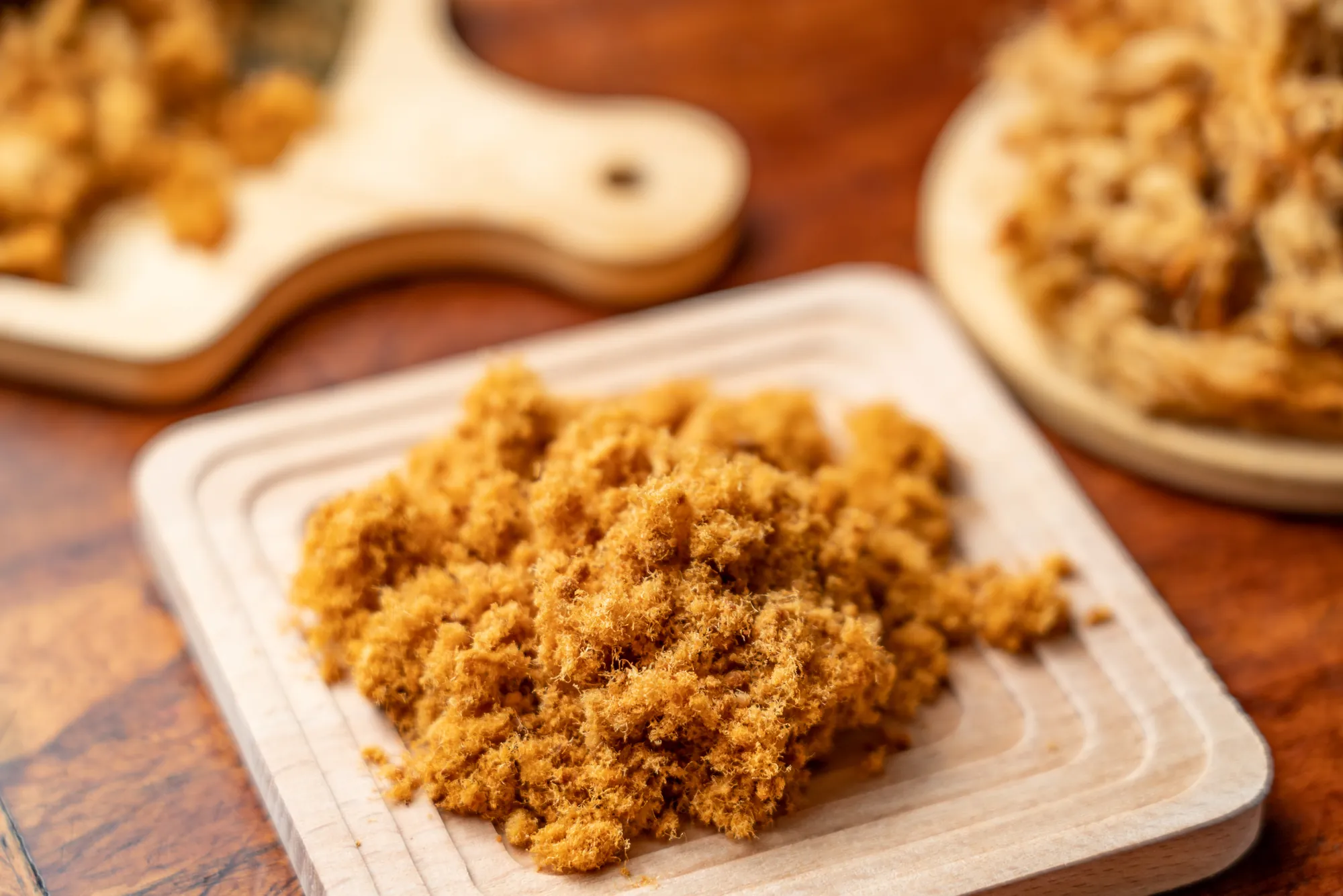 堆疊在木製托盤上的原味金黃肉鬆，質地細緻蓬鬆且纖維分明，是台灣傳統早餐搭配稀飯或夾土司的經典佐料。