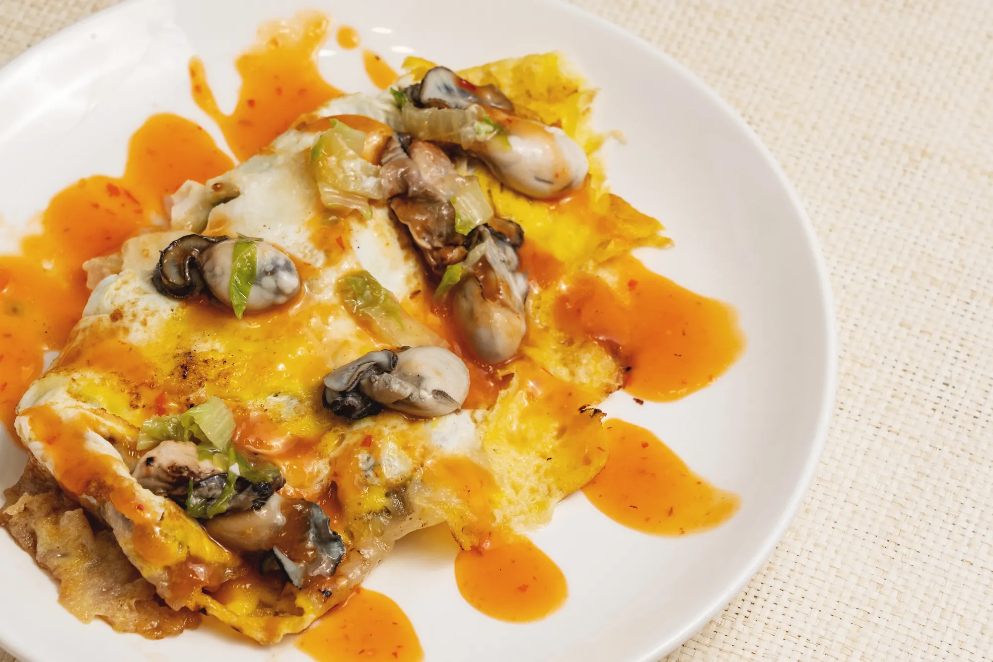 盛裝在白盤中的正宗夜市蚵仔煎，呈現粉漿煎至微焦的酥脆邊緣與軟Q口感，佐以新鮮蚵仔與特調淋醬。