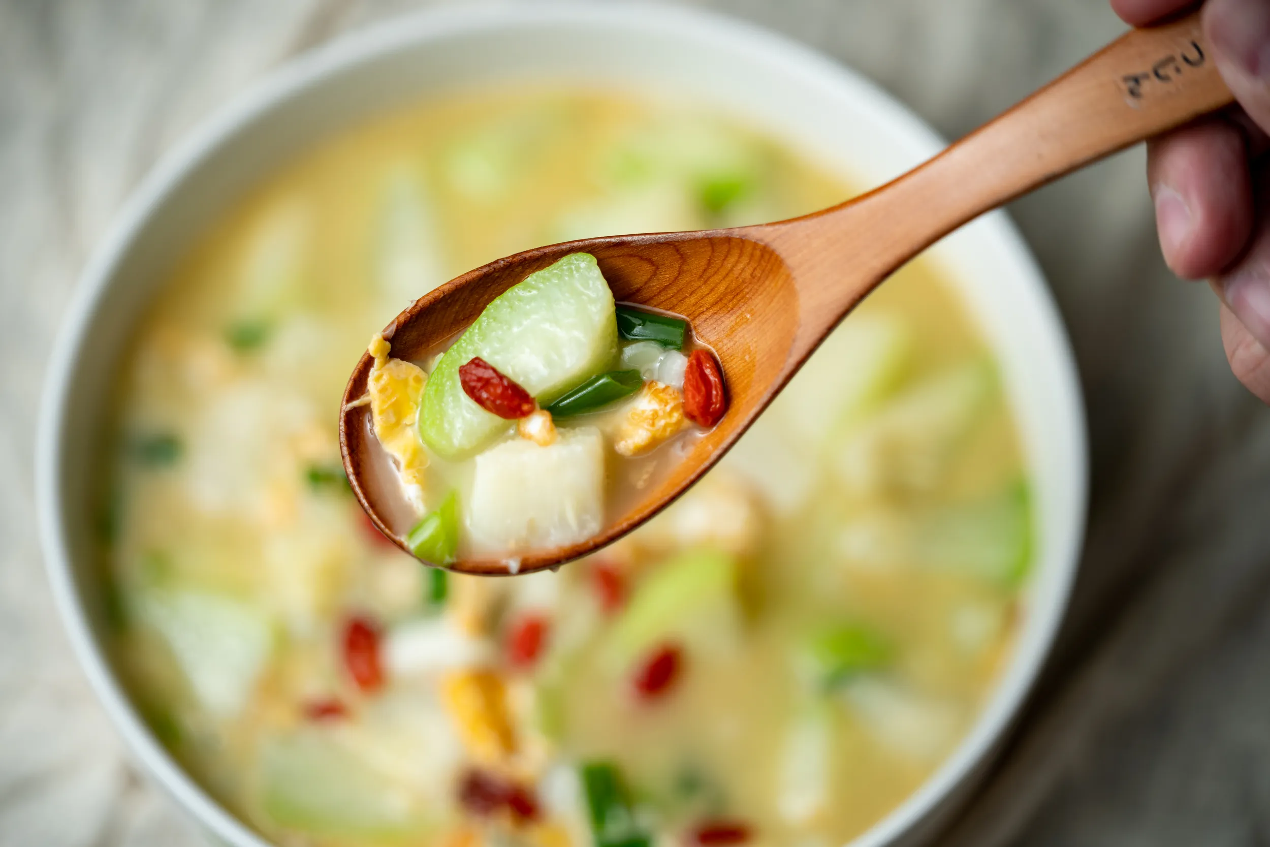 特寫鏡頭展示木湯匙舀起燉煮軟嫩的匏仔（瓠瓜），搭配炒蛋與枸杞點綴，呈現台灣家常料理的清爽風味。