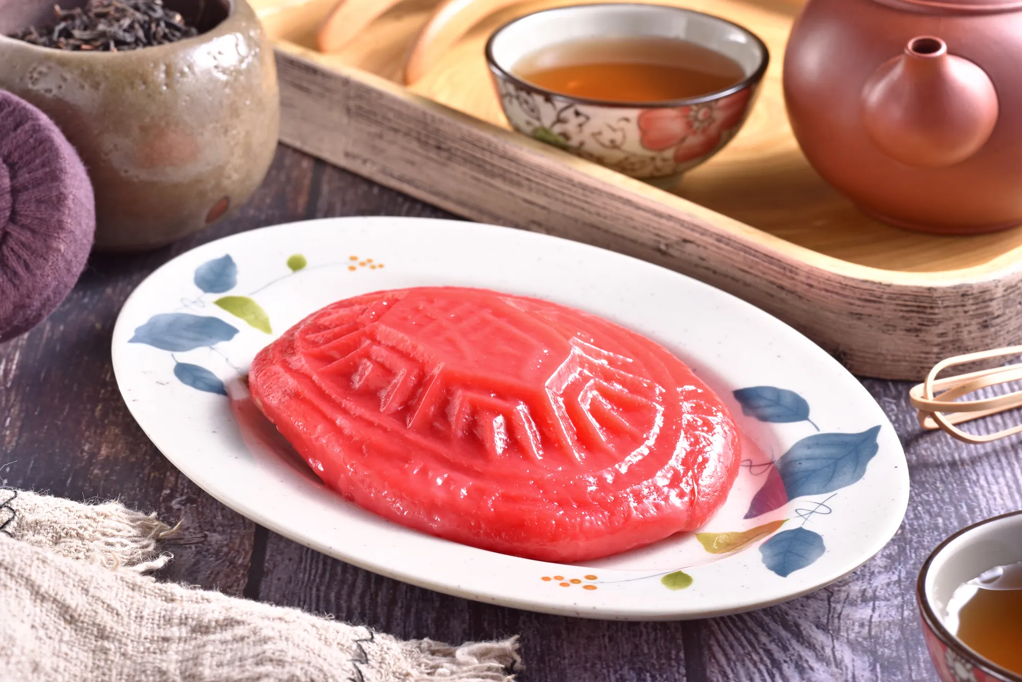呈現經典「台灣紅」色澤的傳統紅龜粿，表面印有精緻龜甲紋路，擺放於陶瓷盤上並搭配中式茶具，象徵長壽與喜氣的台灣在地茶點文化