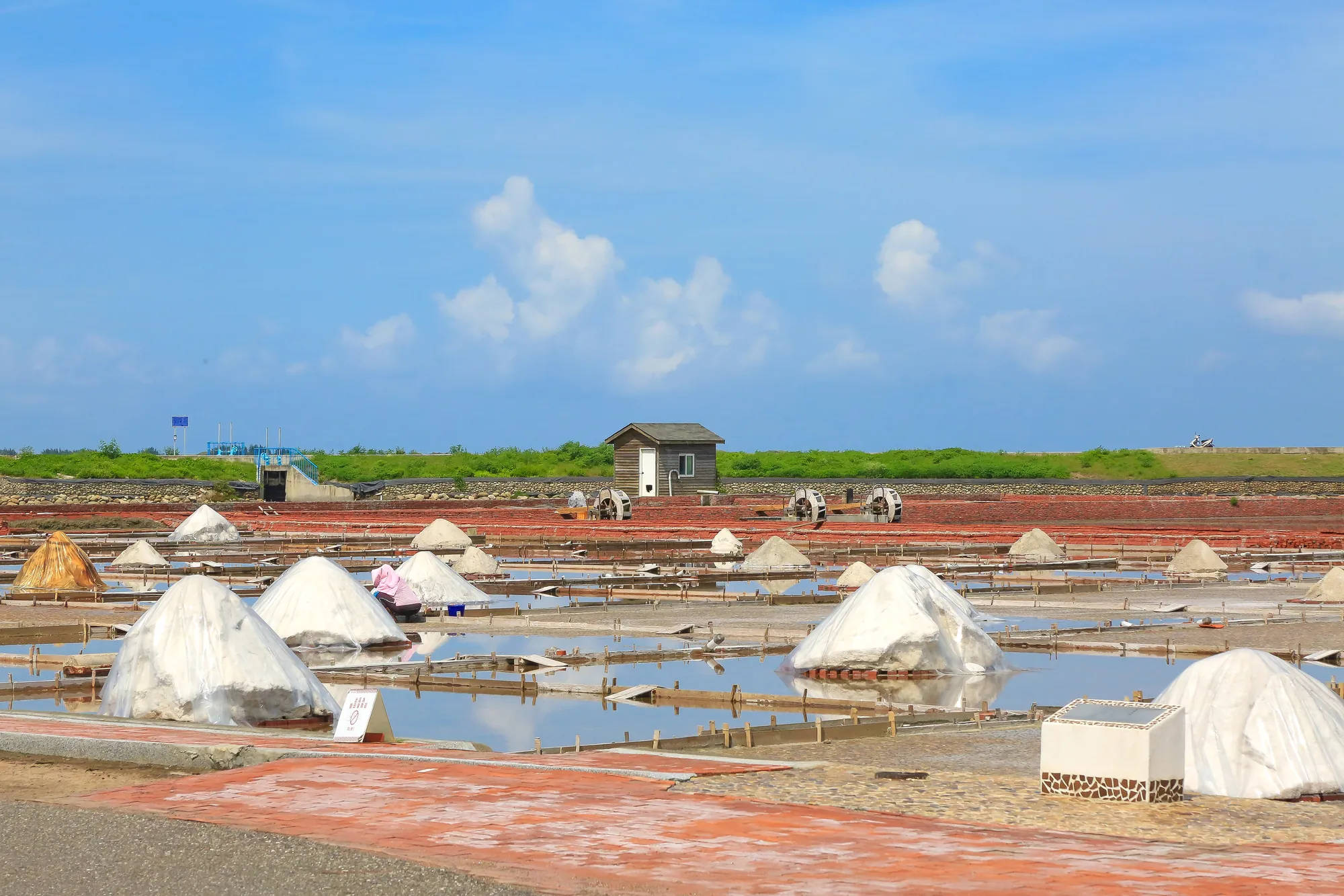 台南及北門區的井仔腳瓦盤鹽田風光，展示棋盤格狀的結晶池與白色小鹽堆，背景可見傳統汲水水車，是台灣現存最古老的人工曬鹽遺址。