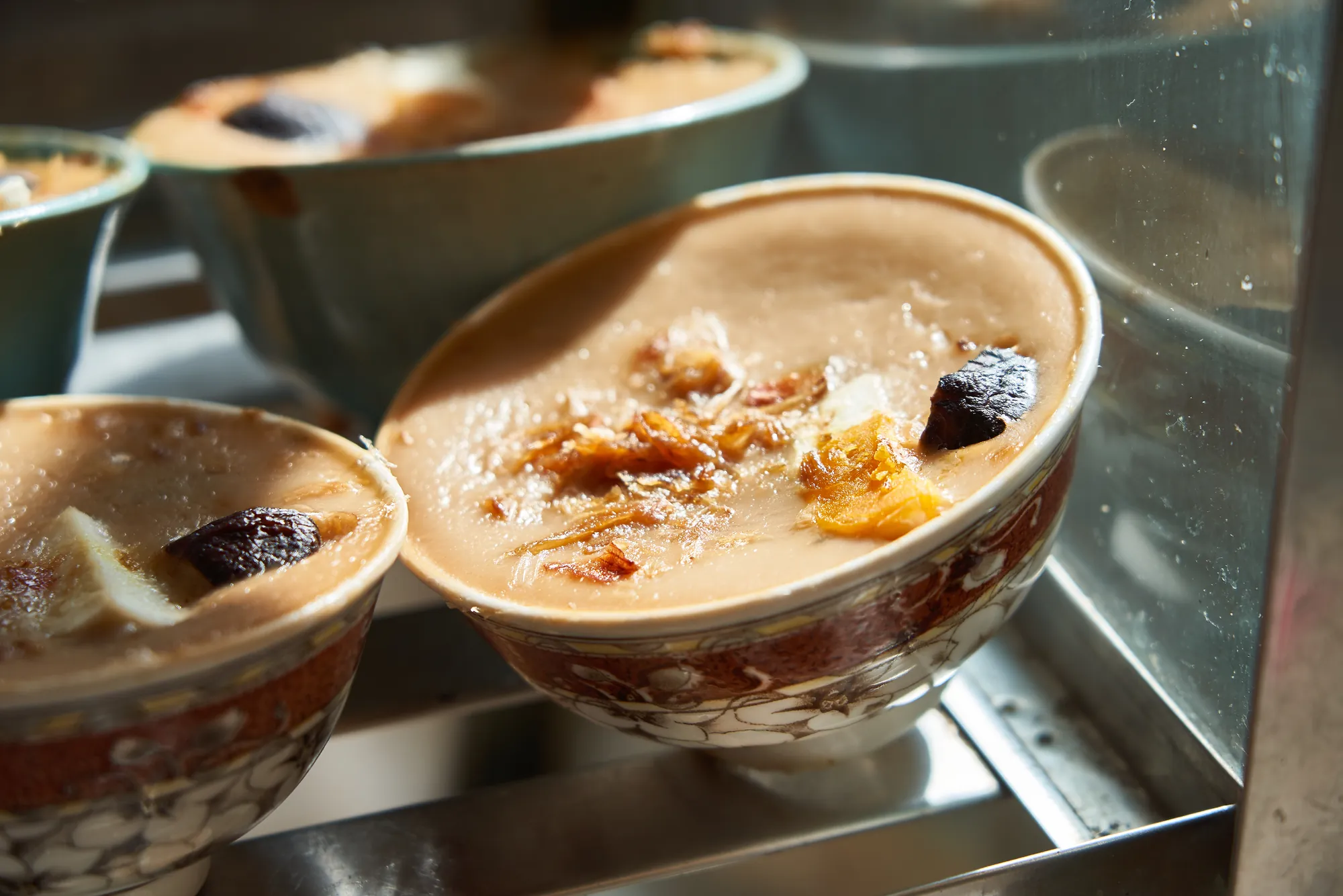 蒸籠內剛出爐的古早味碗粿，深褐色粿體表面鋪有香菇與鹹蛋黃，盛裝於復古瓷碗中，呈現台南風味傳統小吃細節