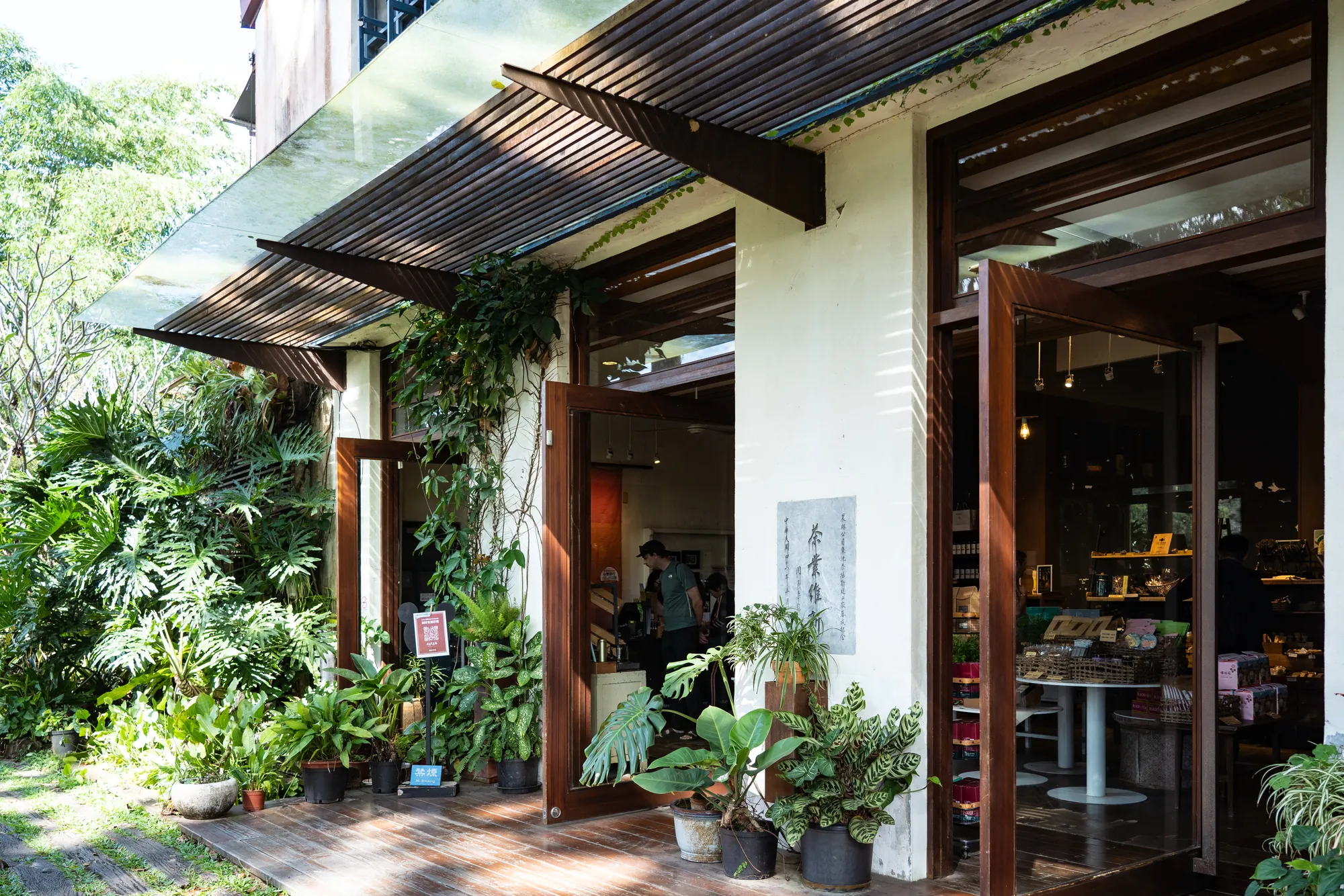 日月老茶廠木造大門入口，周圍環繞綠意盎然的盆栽植栽與自然採光