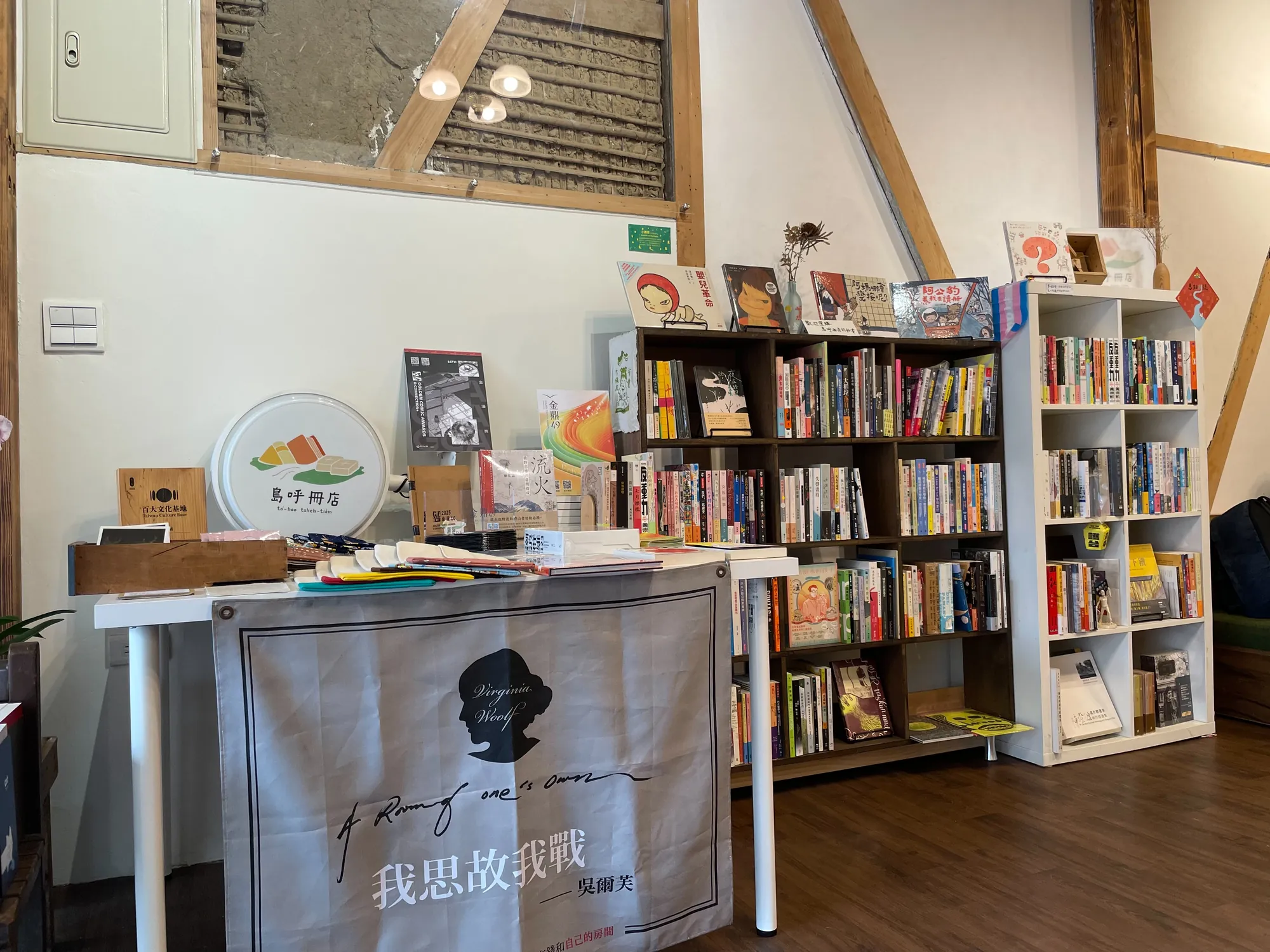 嘉義島呼冊店室內書架細節,展示「島呼冊店」燈箱與掛有吳爾芙名言布條的溫馨獨立書店空間。