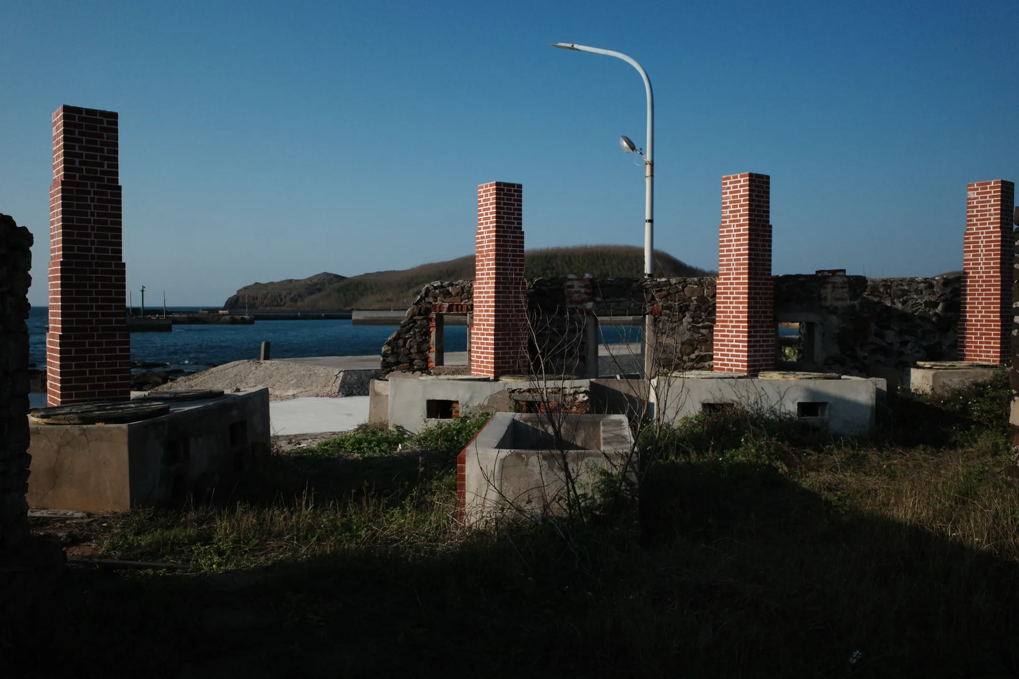 澎湖望安花宅聚落古老魚灶遺跡，展示早期燻魚煙囪與紅磚灶台，背景為湛藍大海
