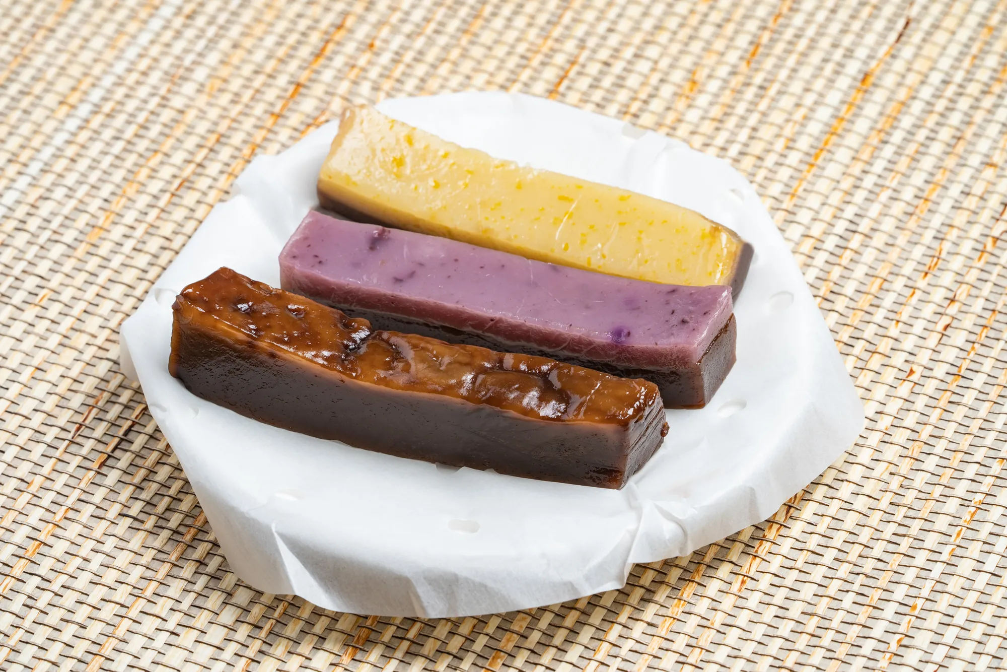 屏東東港傳統名產雙糕潤，包含黑糖、山藥與原味等三種口味長條狀切塊，放置於白色襯紙上。