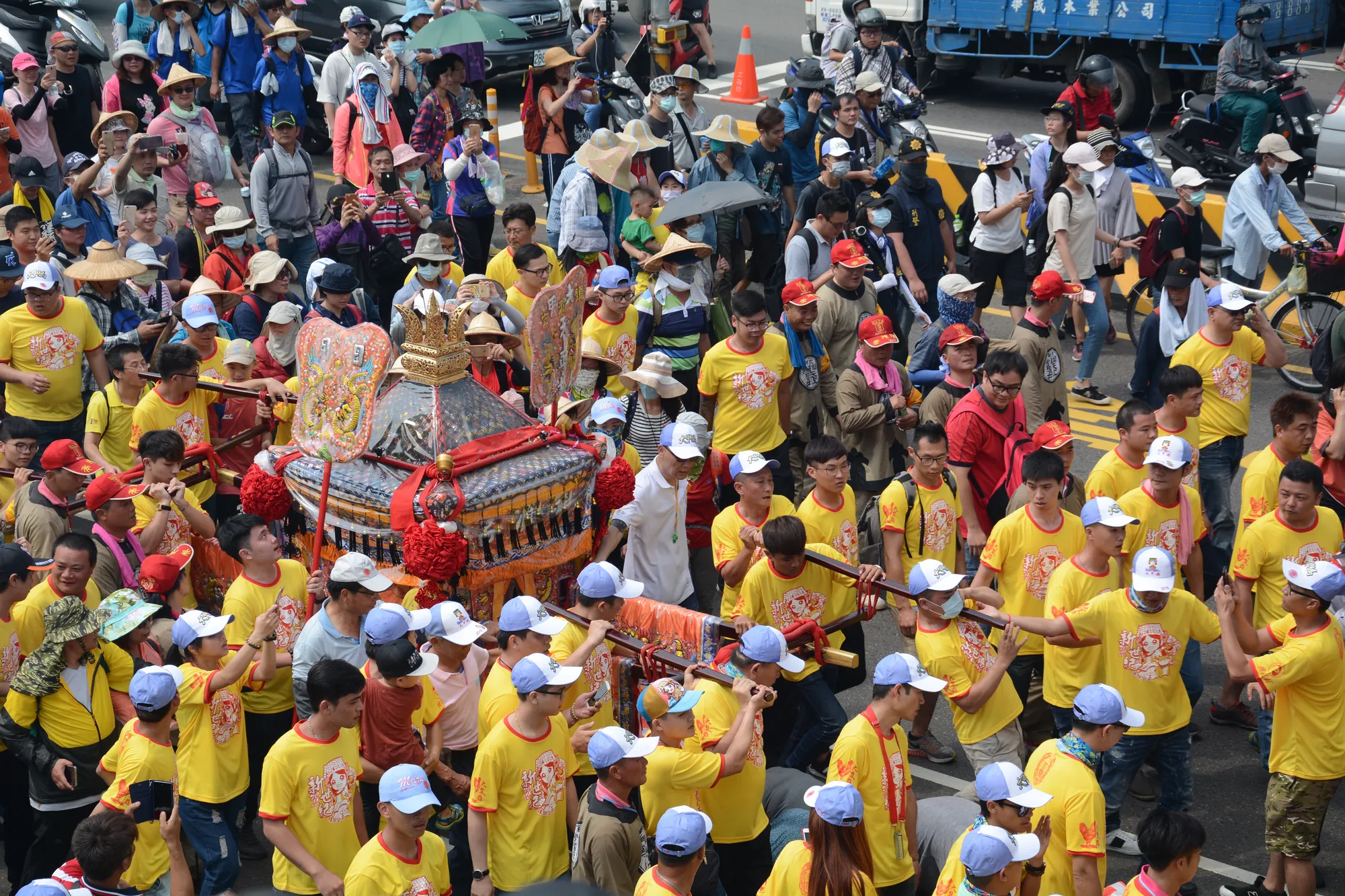 大甲媽祖遶境現場，大批身穿黃色團體服的信眾簇擁媽祖轎輦，展現台灣民間宗教盛況與結緣文化。
