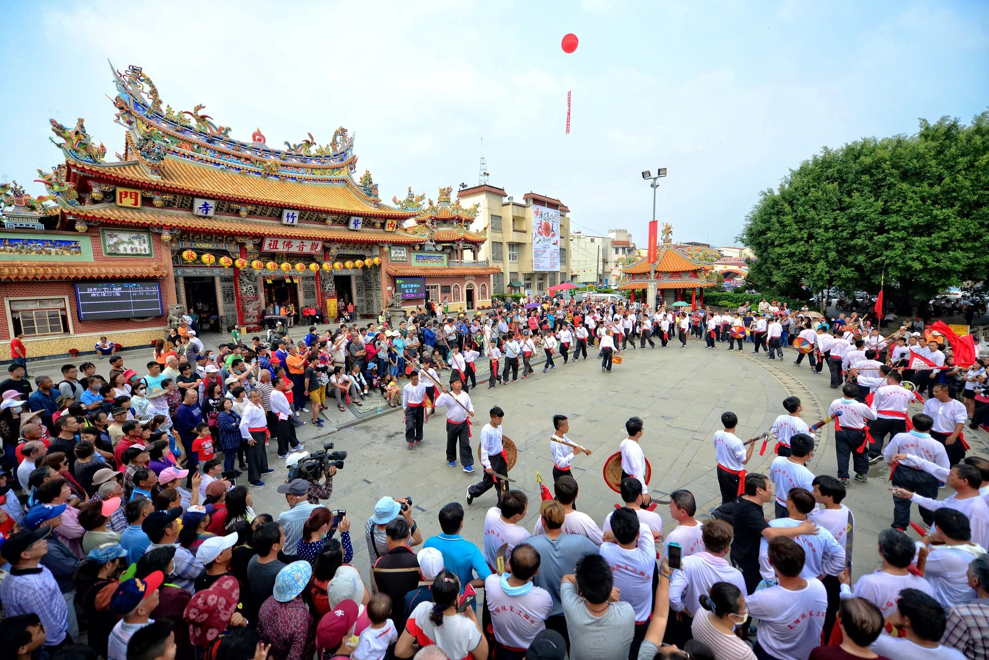 高雄內門紫竹寺前廣場，宋江陣成員圍繞圓圈進行武術陣頭表演，周圍吸引大批信眾與遊客圍觀。