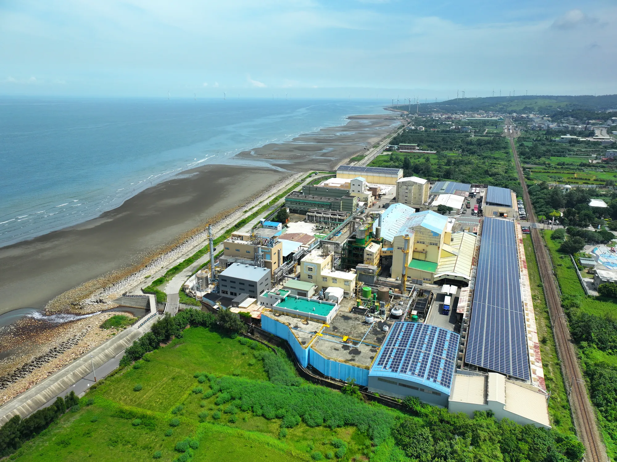 苗栗臺鹽通霄精鹽廠空拍全景，鄰近海岸線並設有大量太陽能板，結合工業生產與綠能開發的廠區景觀。