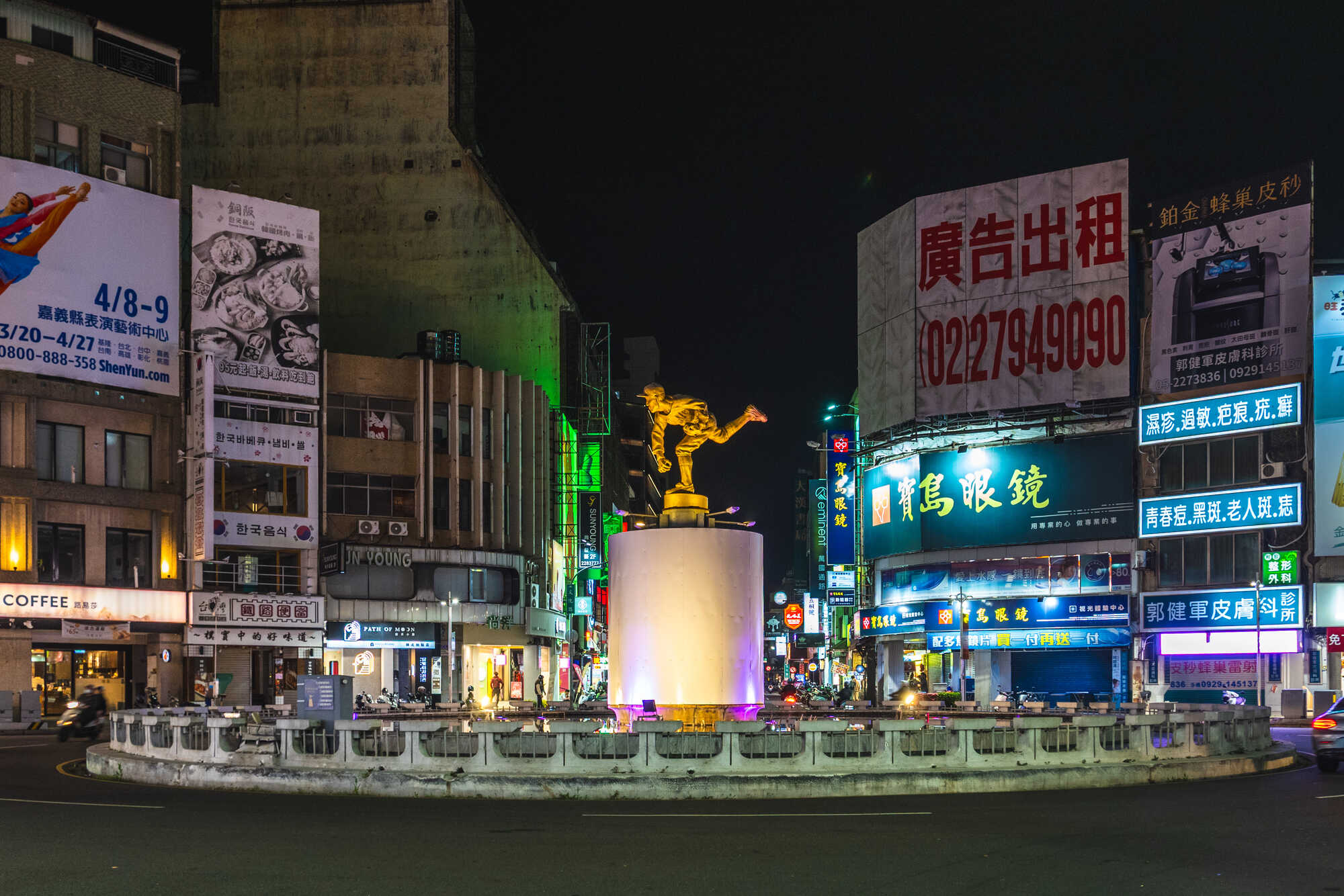 夜晚的嘉義市中央噴水池街景，中央矗立著著名的 KANO 棒球投手金色雕像。