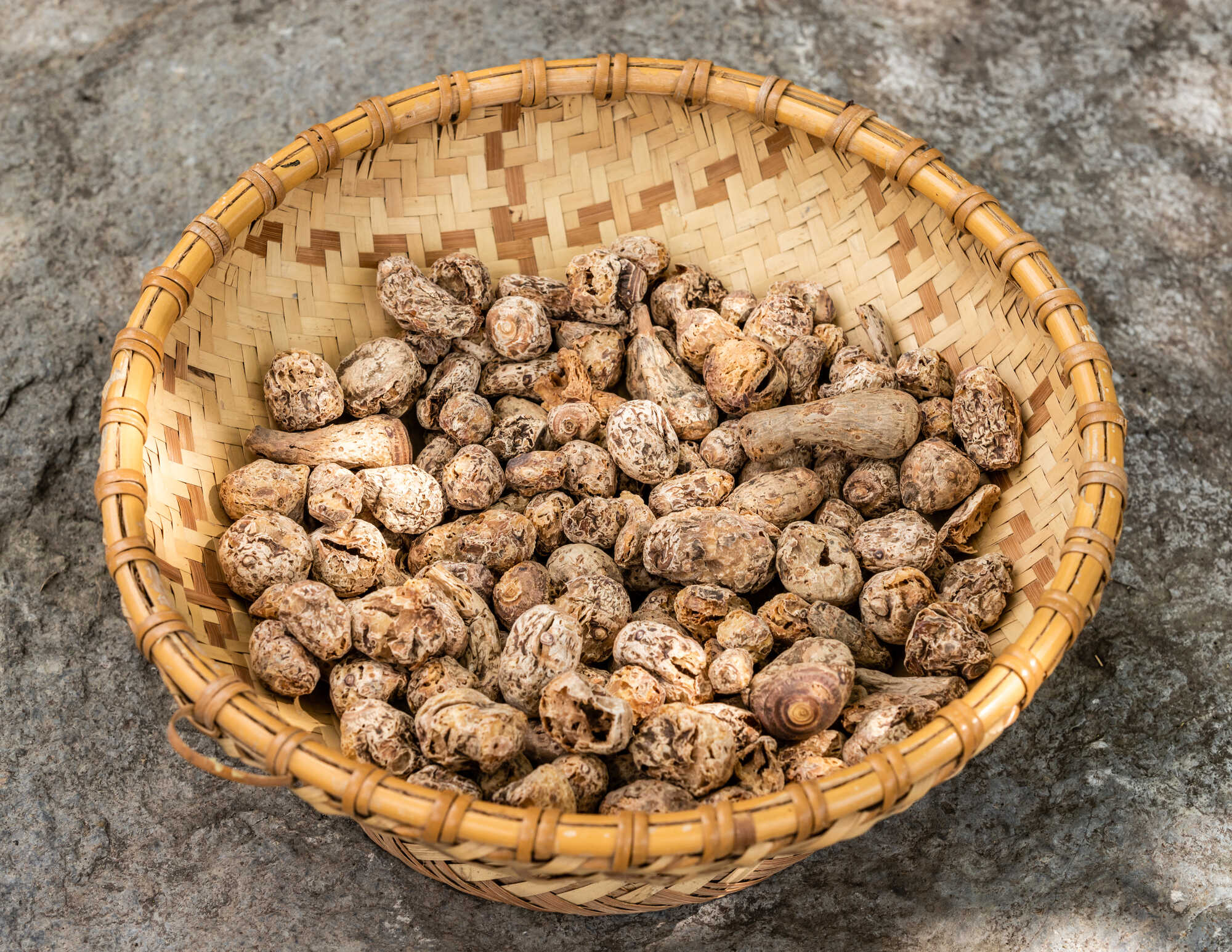 盛裝在竹編籃與綠葉上的深褐色燻製芋頭,呈現傳統原住民食材的原始樣貌。