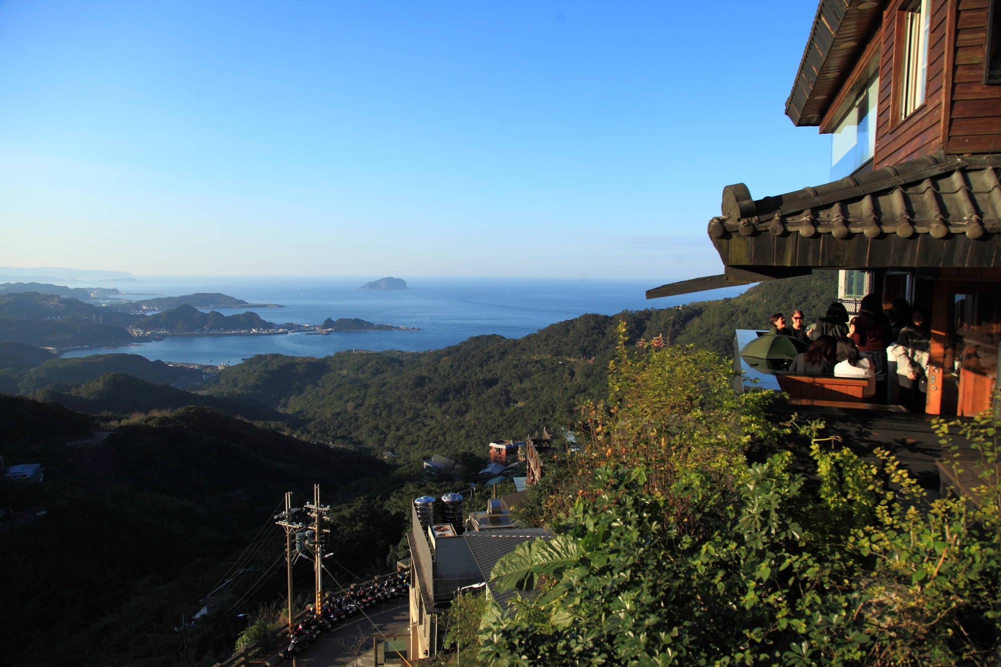 九份山城眺望北海岸景色，山巒與湛藍海面交會，傳統建築依山而建。