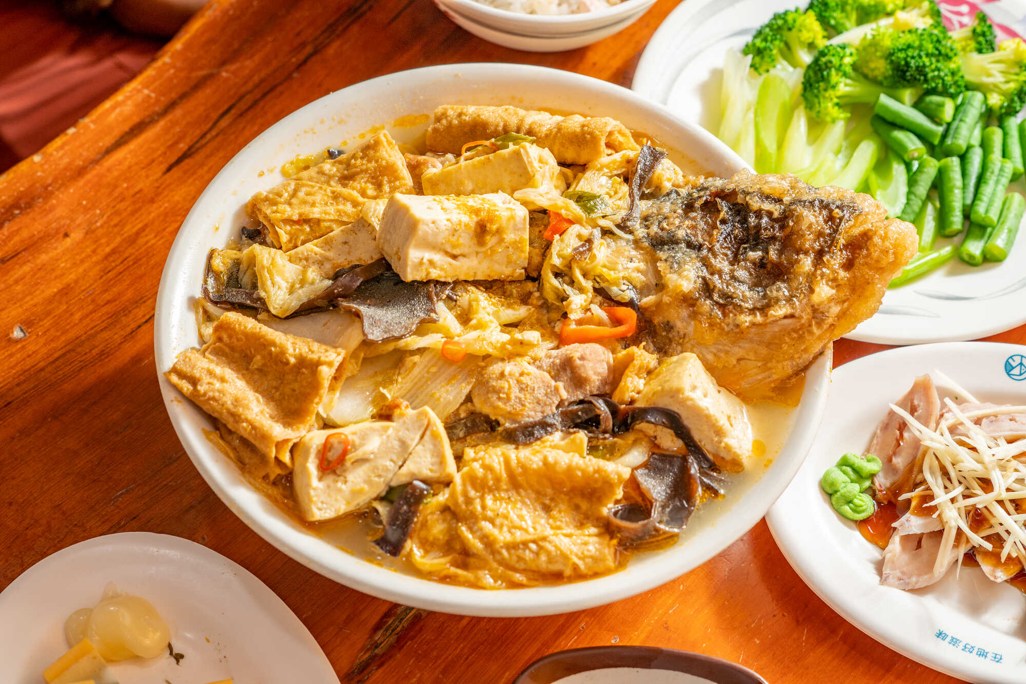 台灣傳統砂鍋魚頭，酥炸魚頭搭配豆腐、豆皮、白菜與木耳，盛裝在濃郁湯汁中。