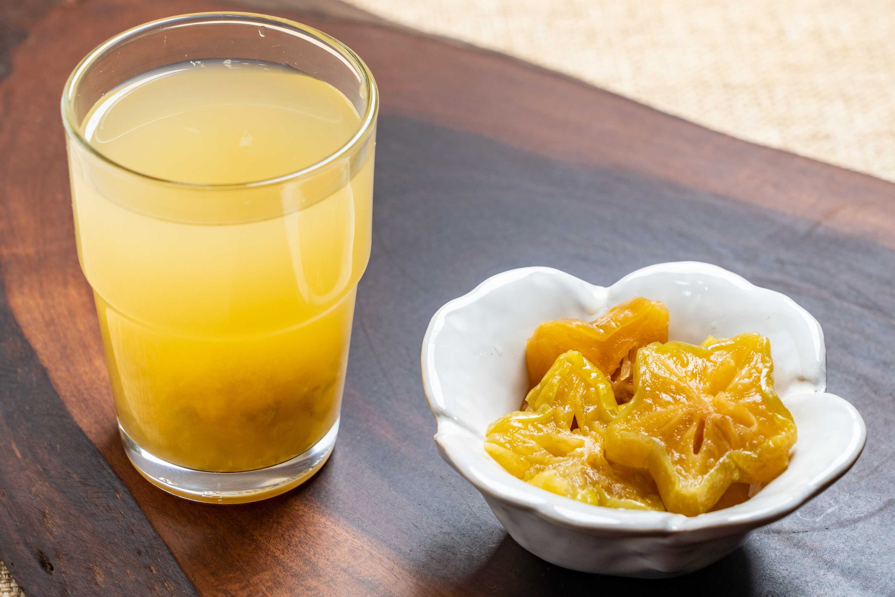 台灣傳統楊桃汁,玻璃杯盛裝金黃色楊桃飲品,旁邊擺放一碗星形切片的醃漬楊桃。